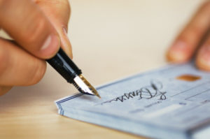 Man signing check --- Image by © Whisson/Jordan/Corbis